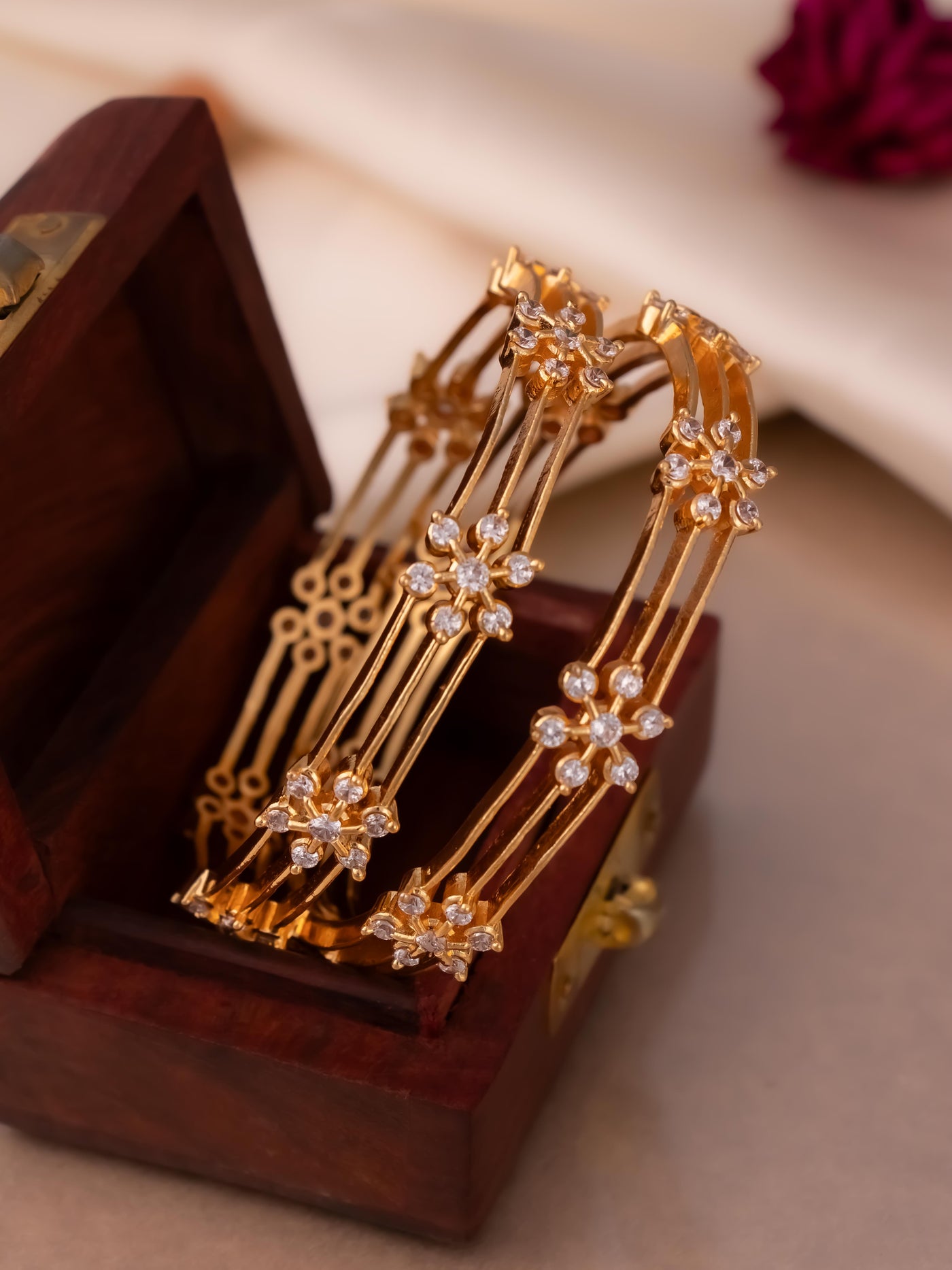 Trending flower bangle in gold plating with white colour ad stone studding.

